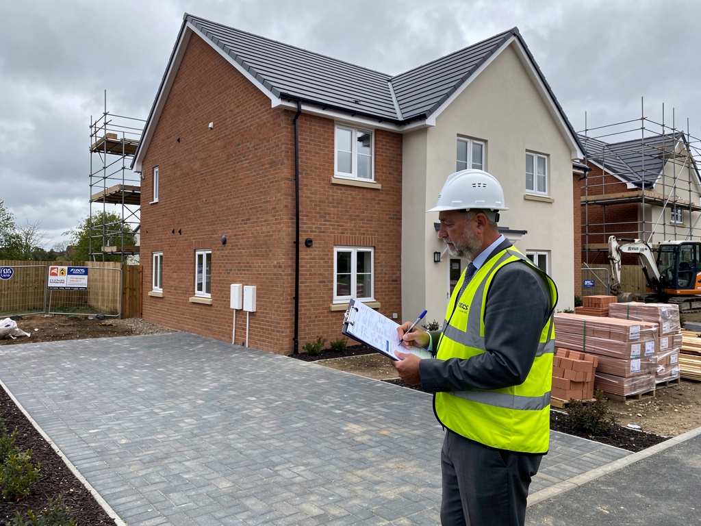 RICS chartered surveyor inspecting a new build home in England with clipboard checking quality defects